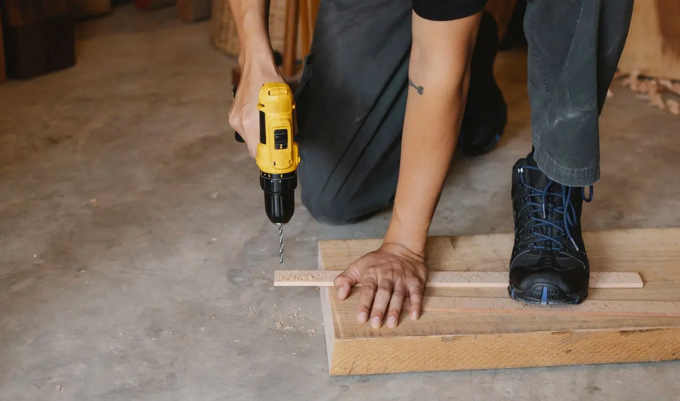 Close-up of a person drilling a wooden board